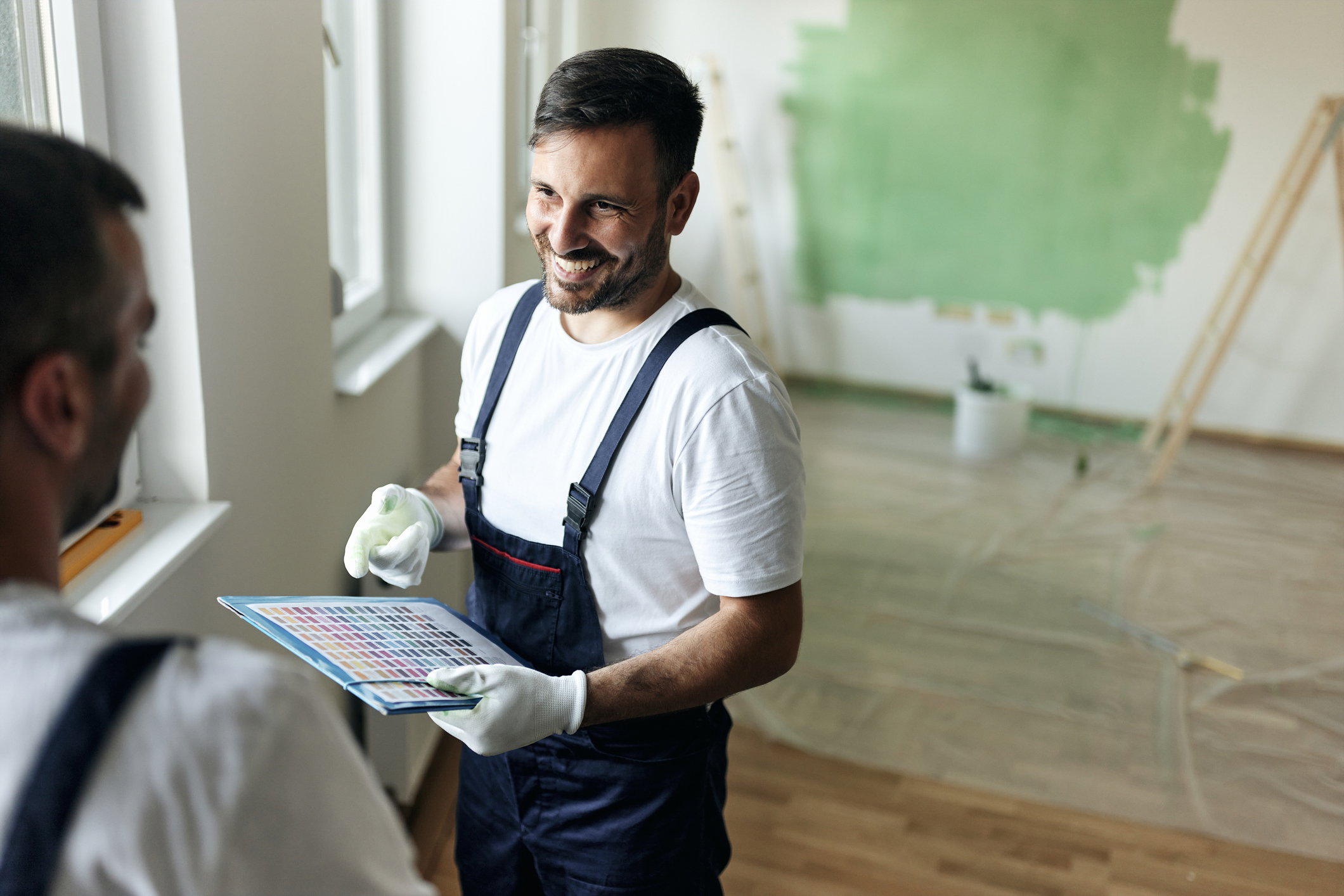 Happy house painters communicating while choosing colors during home renovation process. Copy space.